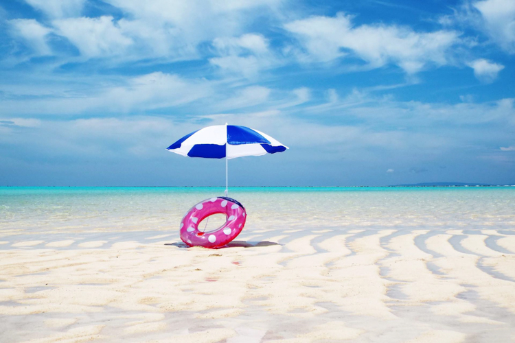 ヨロン島の白い砂浜に立つパラソルと浮き輪の写真